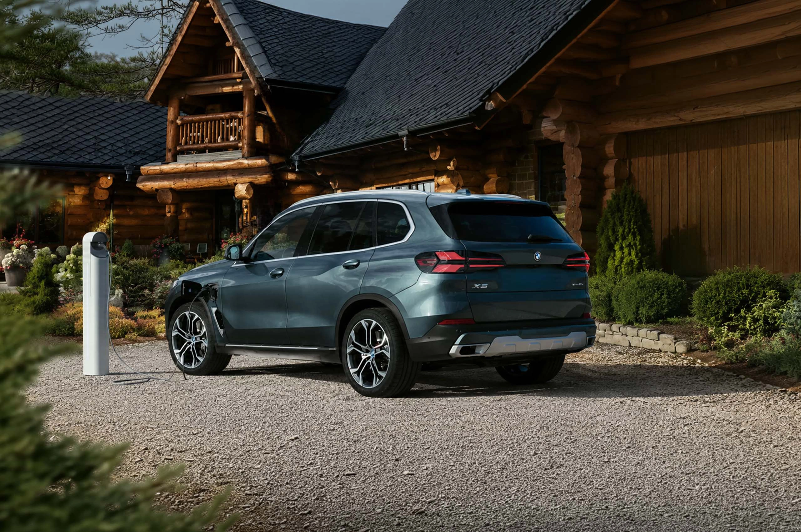 Professionnel consultant son téléphone appuyé sur le capot d'une BMW.
