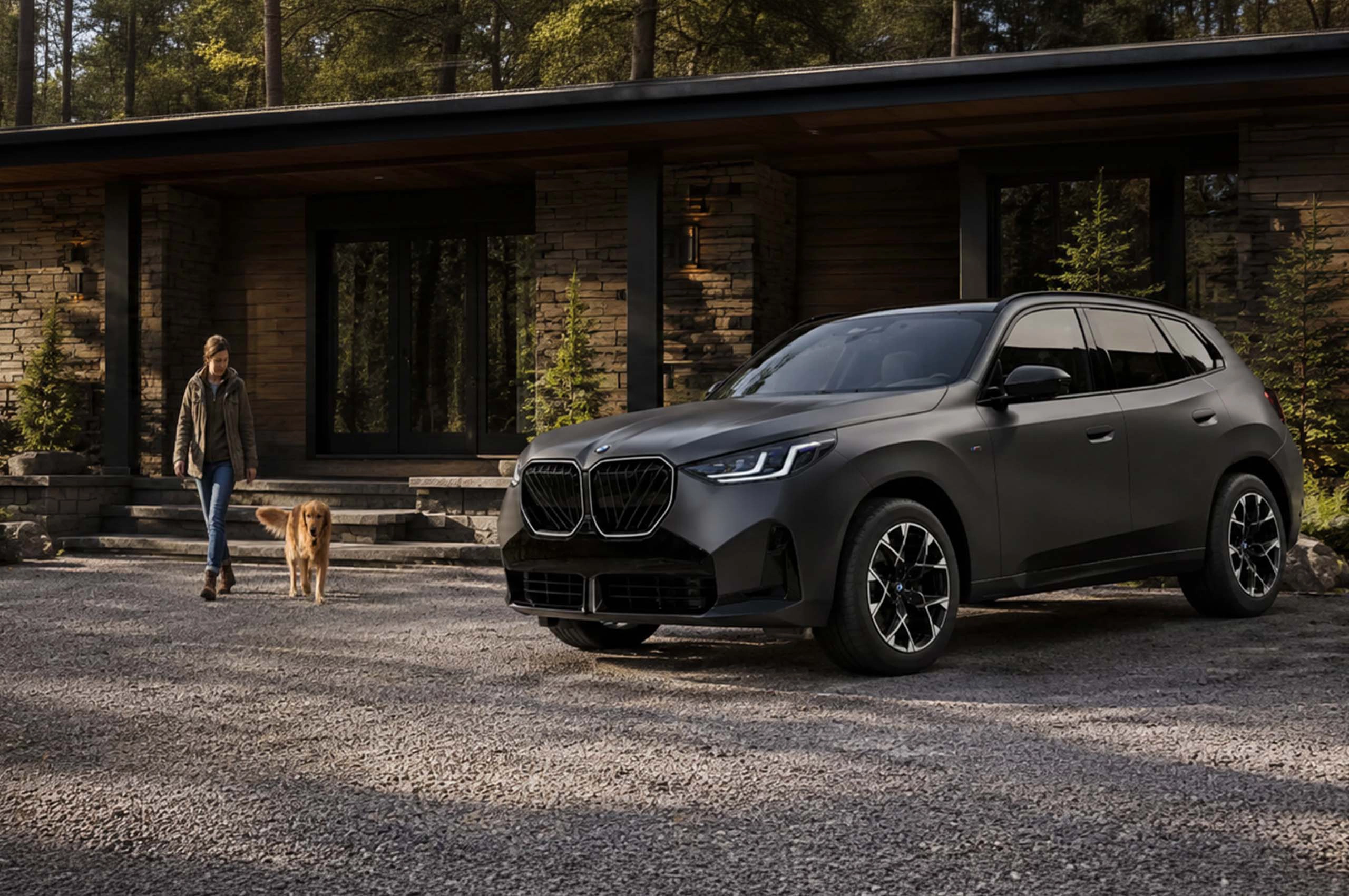 BMW réfléchie dans un étang devant une borne de recharge murale.