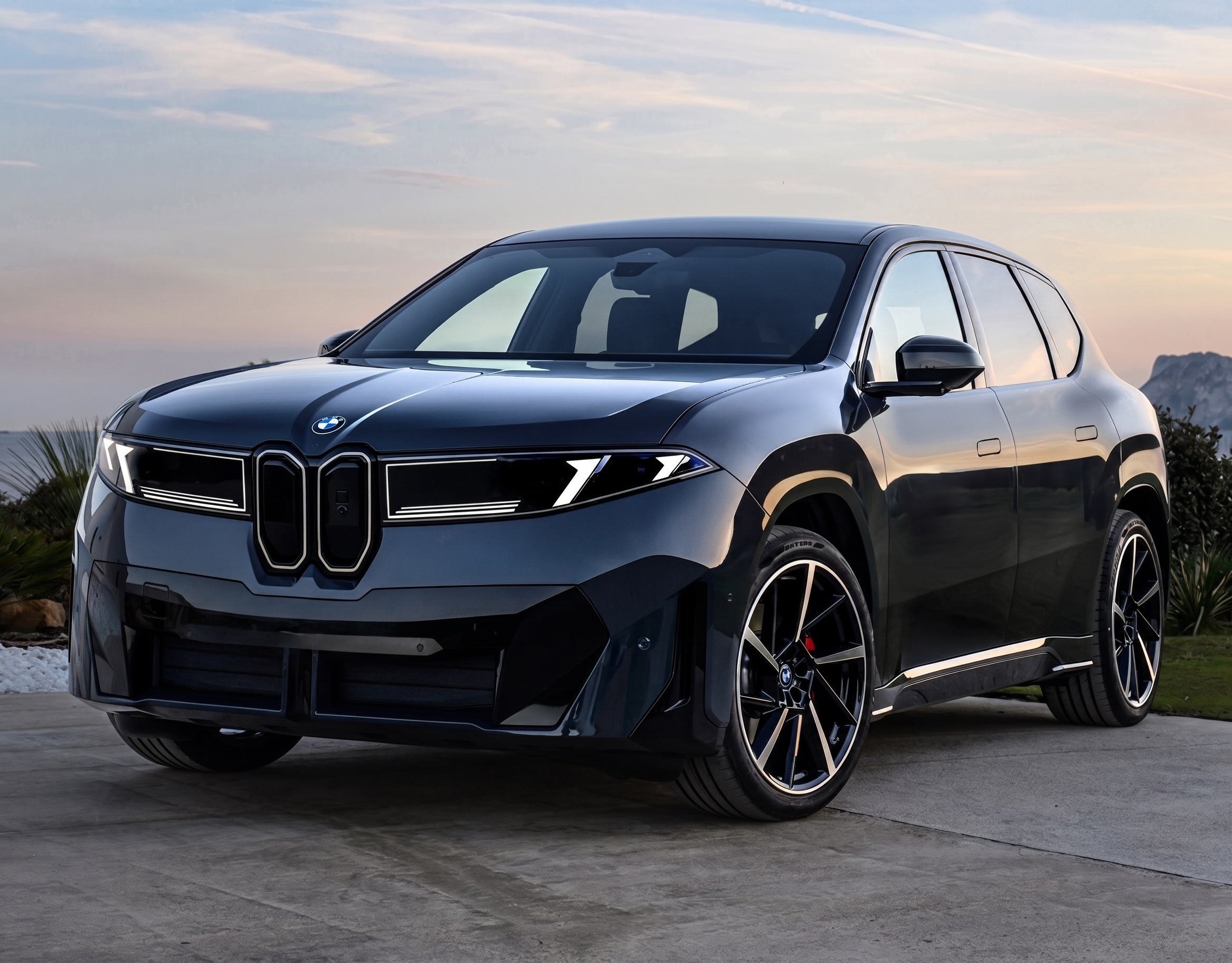 A black iX3 in front of a sunset.