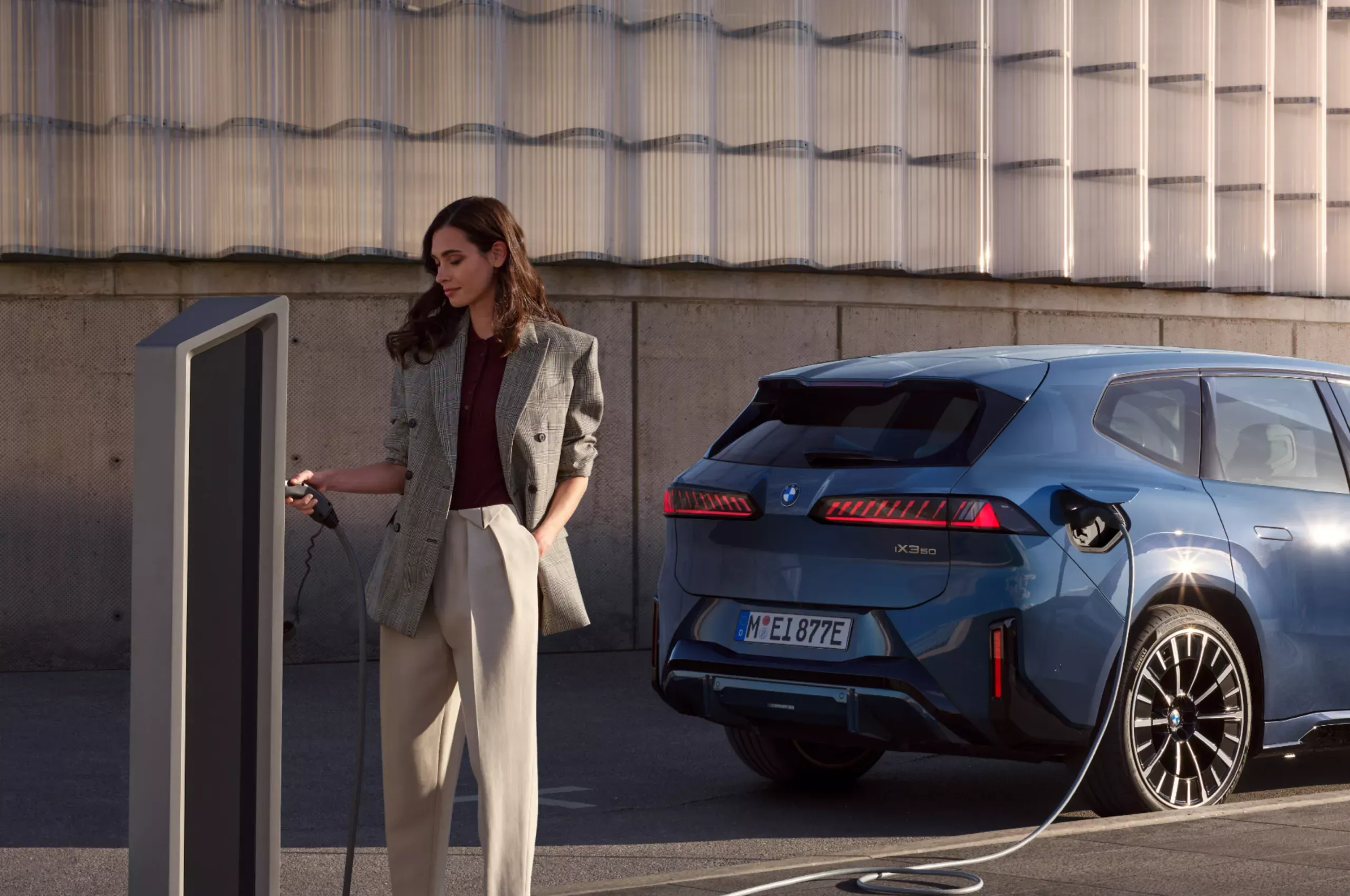 Professionnel consultant son téléphone appuyé sur le capot d'une BMW.