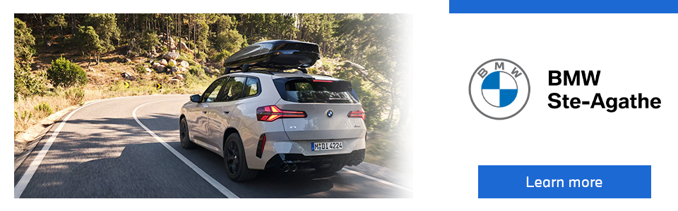 A BMW SUV with a roof box driving on a forest road.
