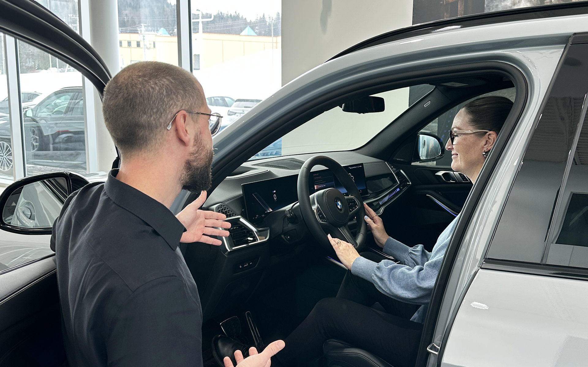 Conseiller BMW expliquant les fonctionnalités d’un véhicule à une cliente chez BMW Sainte-Agathe