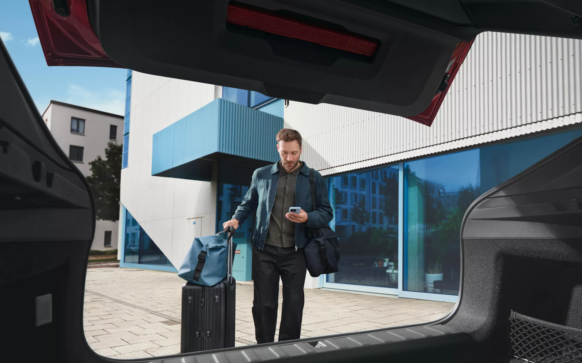 Homme utilisant la BMW Digital Key sur son téléphone pour déverrouiller son véhicule avec ses bagages