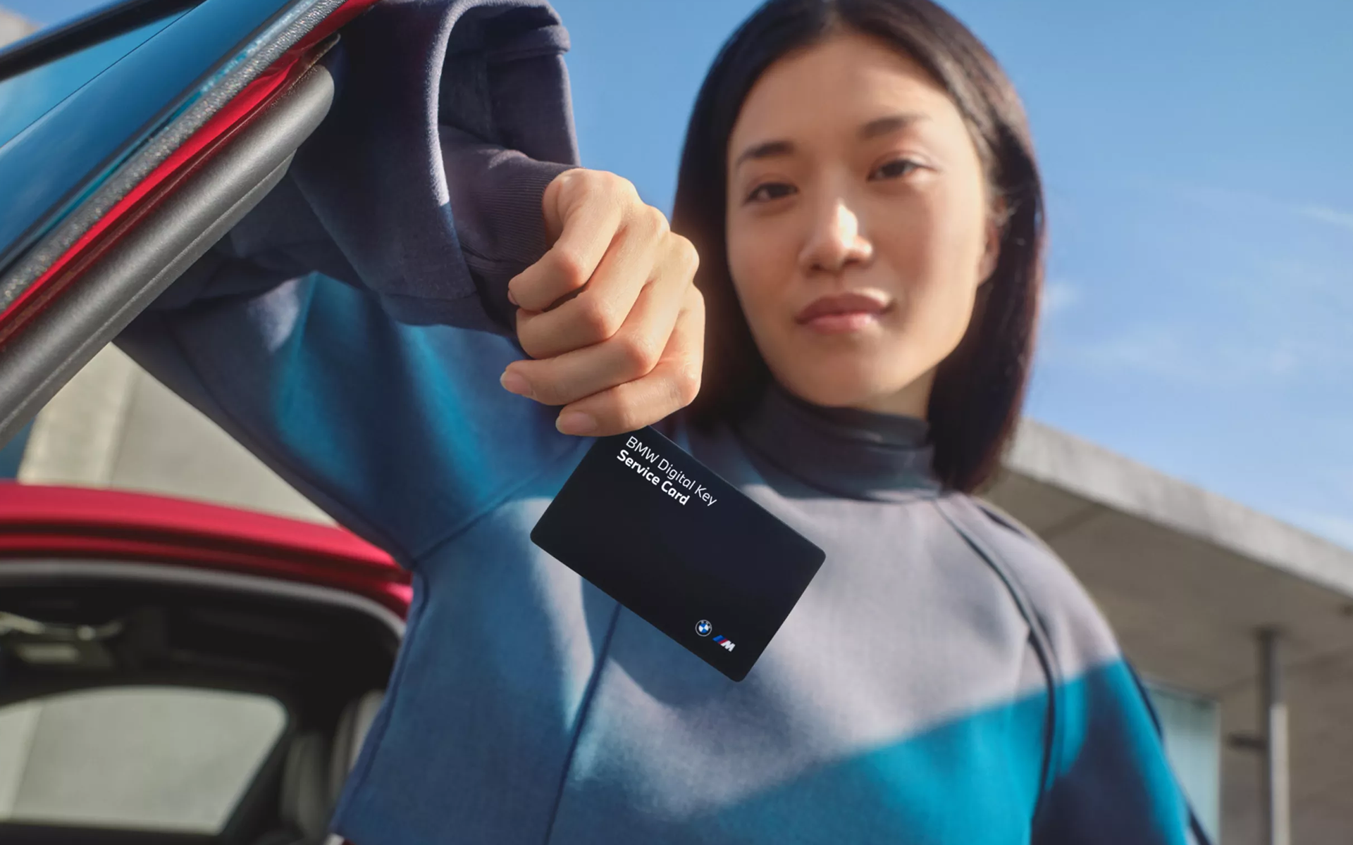 Conductrice présentant la BMW Digital Key Plus devant son véhicule – technologie intelligente et sécurisée