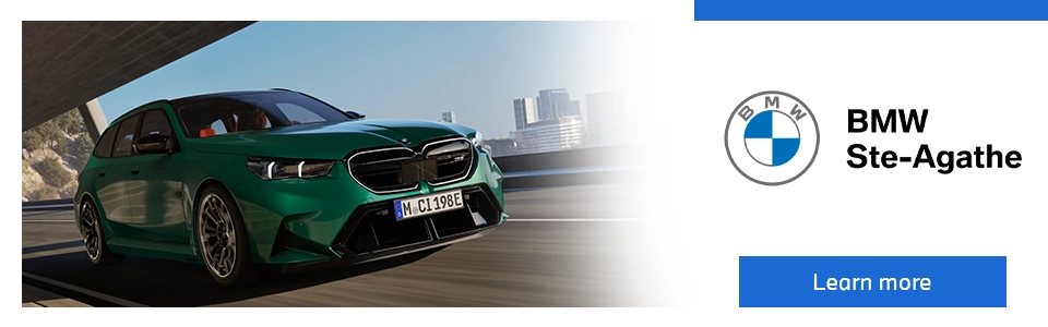 New 2025 BMW M5 Touring driving on the road, featured by BMW Ste-Agathe with Learn More button.