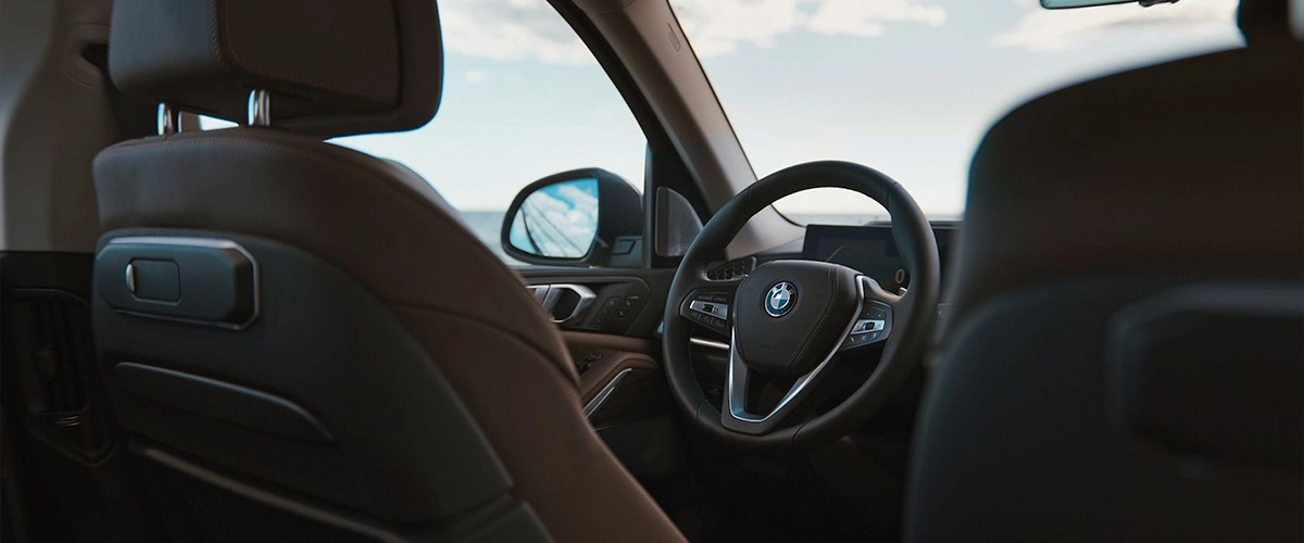 Luxury interior of 2025 BMW X5, featuring leather seats and modern steering wheel.