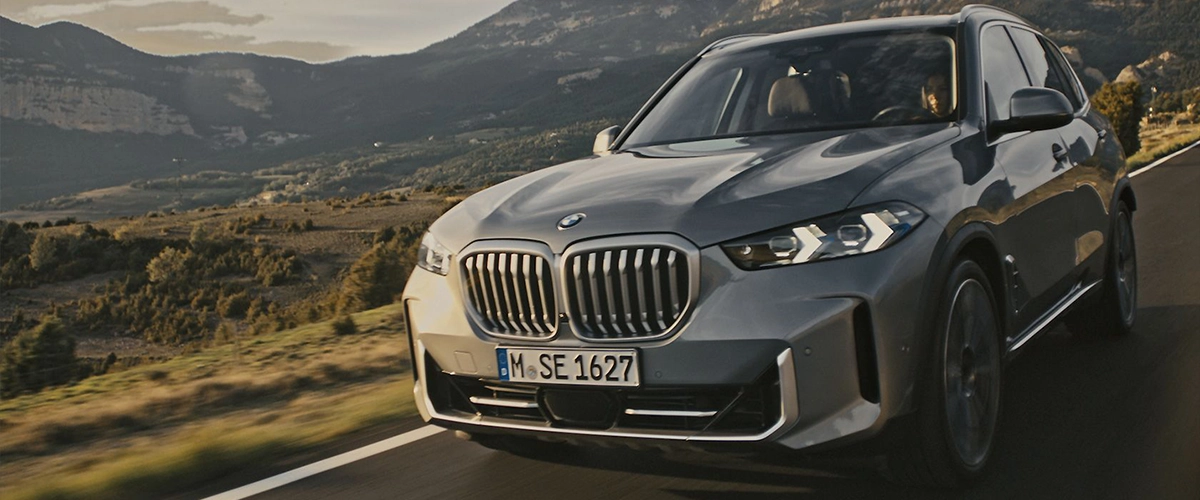 2025 BMW X5 driving on mountain road, showcasing its performance and stylish exterior.