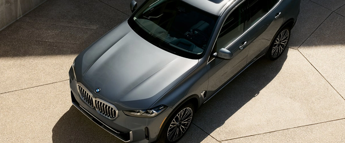 Aerial view of 2025 BMW X5 parked on a concrete surface, showcasing top-down elegance.