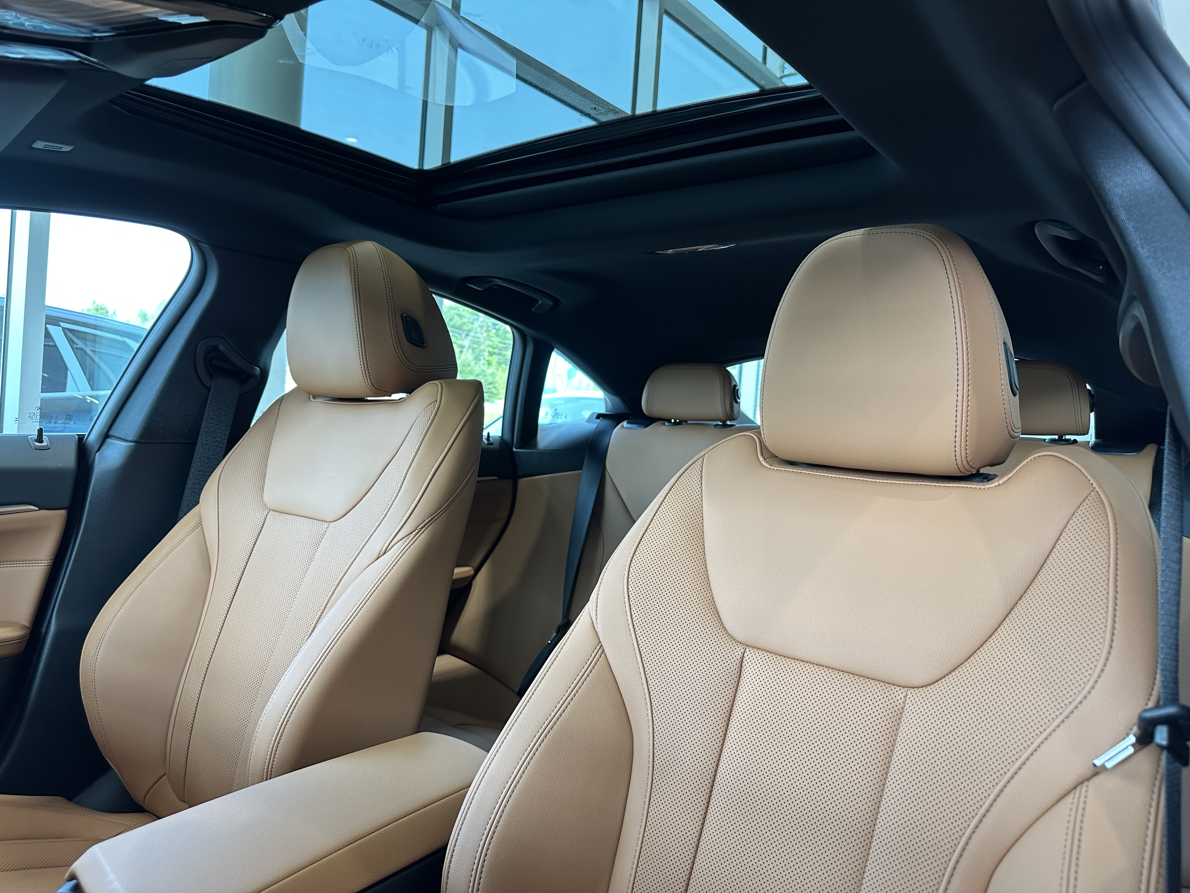 Sièges avant en cuir beige d’une BMW avec toit ouvrant panoramique.