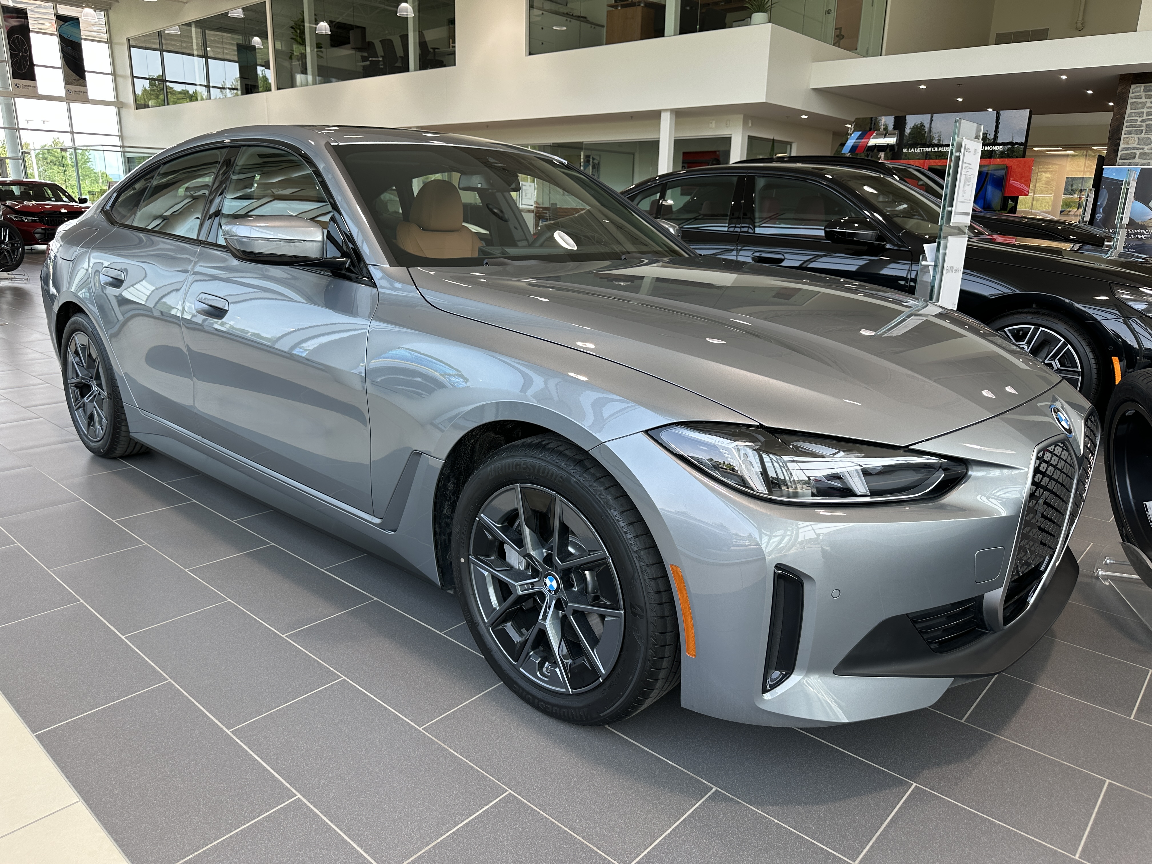 BMW grise exposée dans une salle de montre, vue de trois-quarts avant.