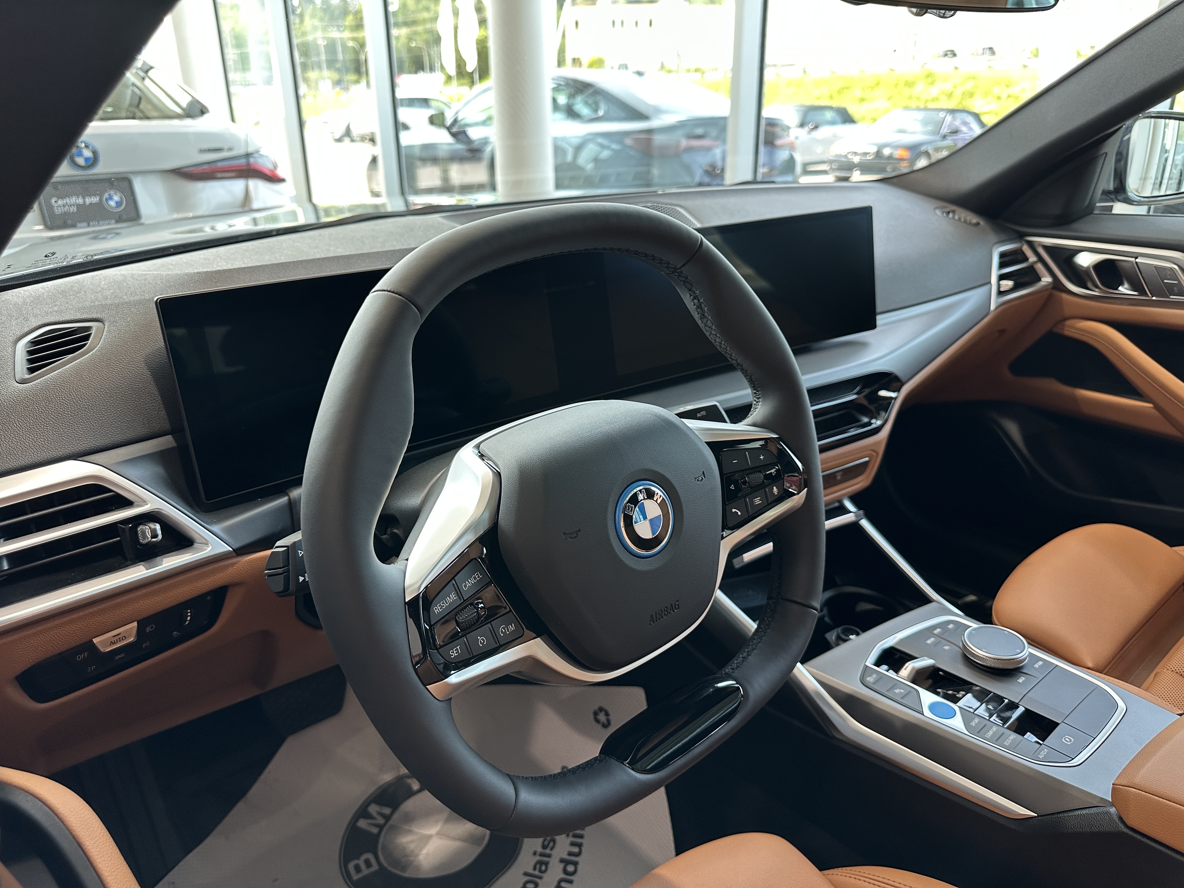 Intérieur d’une BMW avec volant multifonction, double écran numérique et sellerie en cuir brun.