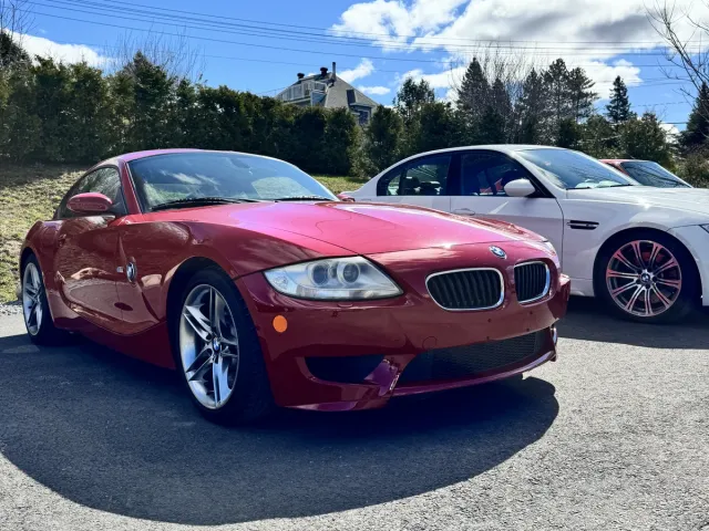 BMW Z4 rouge carmin, trois quarts avant, dans le stationnement de la concession.
