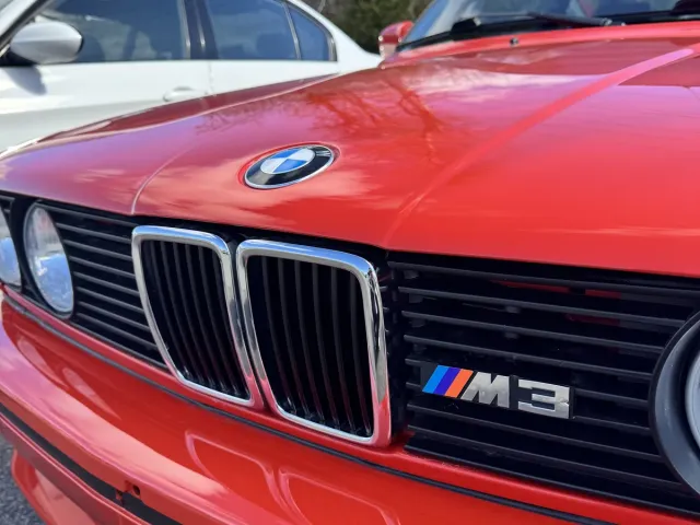 Calandre à double haricot et badge M3 sur le capot de la BMW M3 E30 rouge.